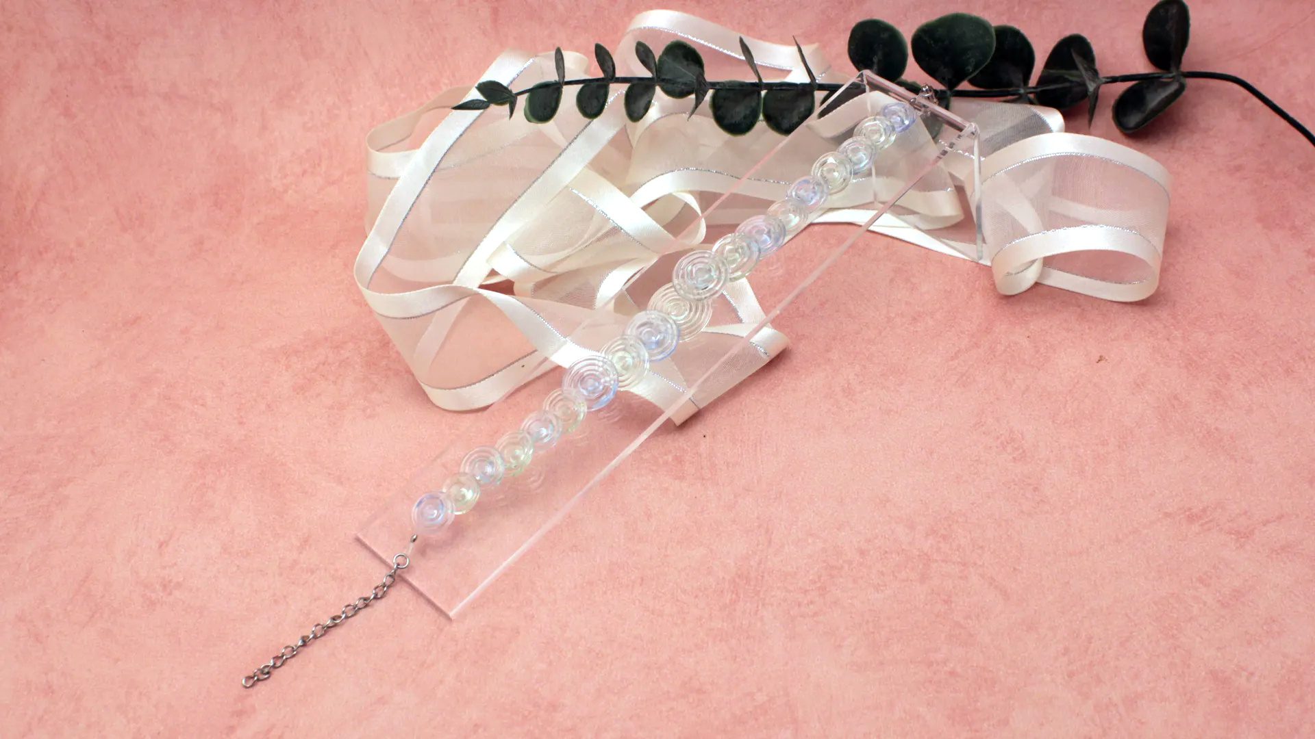 Bracelet en perles spirales transparentes en verre recyclé avec pièce de 50 centimes pour montrer l’échelle.
