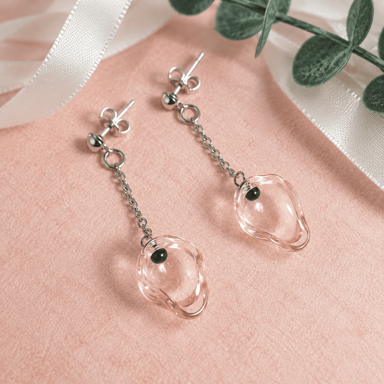 Boucles d’oreilles pendantes Éclat Rosé en verre recyclé transparent rosé, créées à partir d’une flûte à champagne avec petites perles noires en verre et montage acier inoxydable.